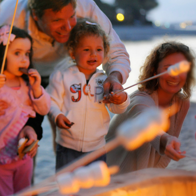 Family roasts S'mores on an open fire